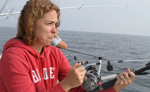 Focused young woman reeling in fish aboard Reel Action - the best charter fishing service on Lake Michigan. Making memories to last a lifetime